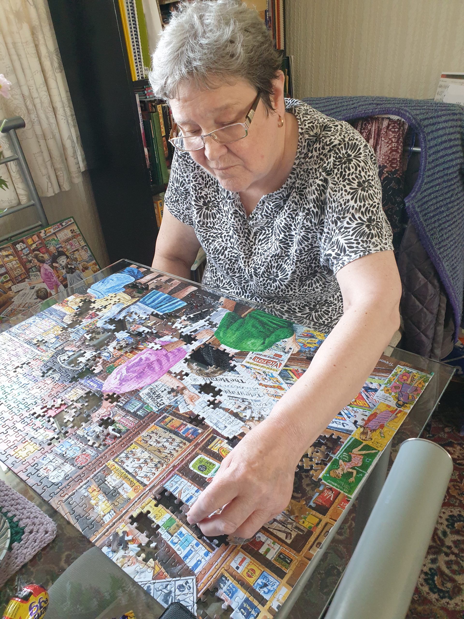 Woman wearing glasses sitting doing a jigsaw