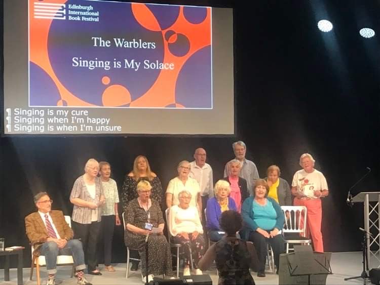 A group of 13 singers performing on the stage at Edinburgh International Book Festival 